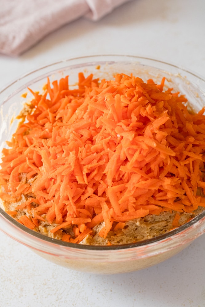 Carrot cupcakes batter with grated carrots on top.