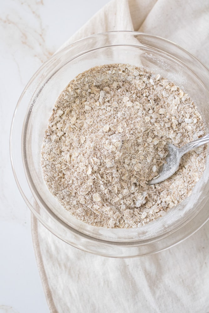 Mixed dry ingredients for oat topping in a bowl with a spoon.
