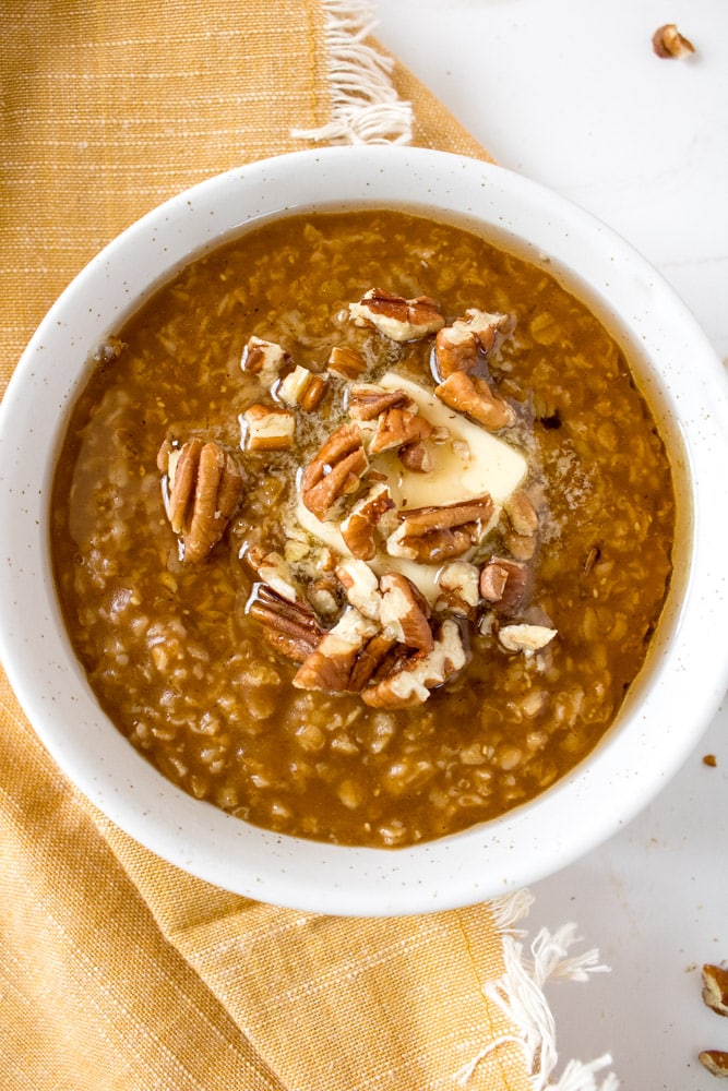 Pumpkin spice oatmeal in a bowl with butter and pecans.