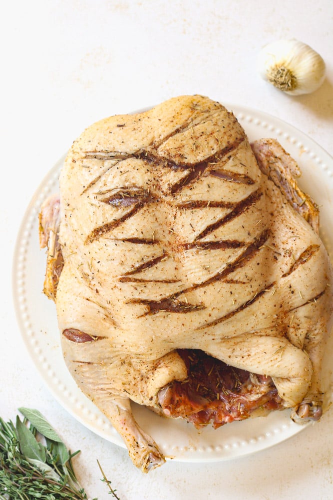 Herb rubbed Whole duck on a plate.