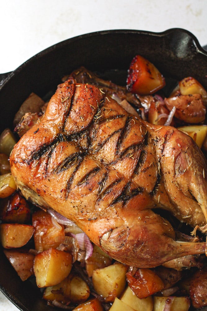 Whole roasted duck in a cast iron skillet.