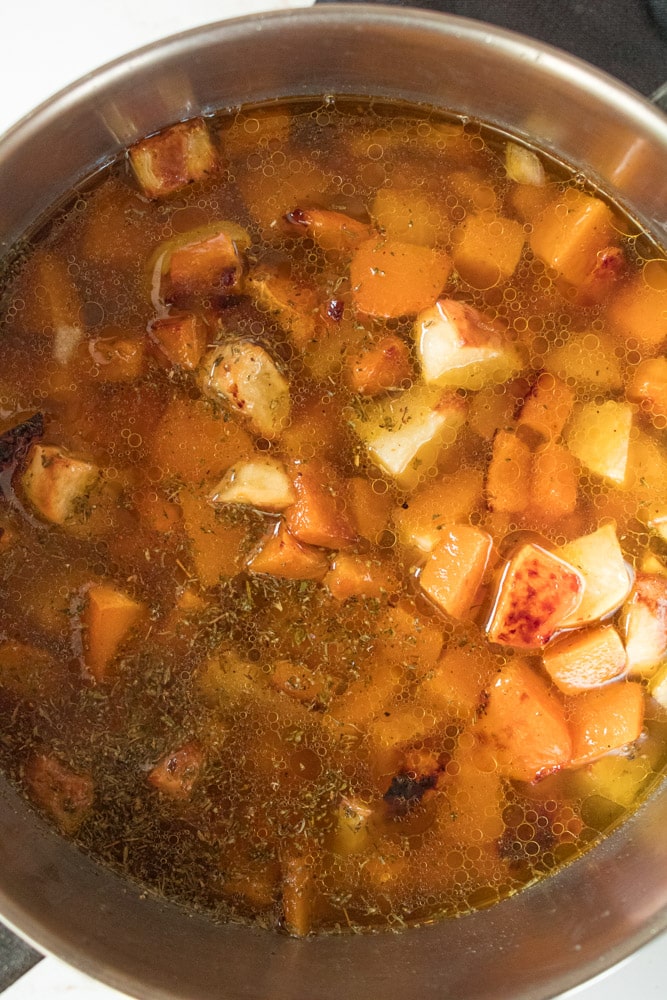 Cooked veggies and chicken broth in a pot.