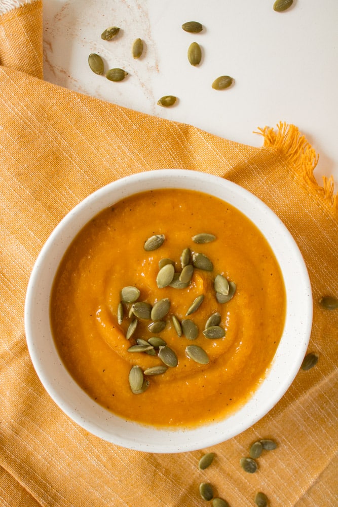Roasted butternut squash soup in a bowl with pumpkin seeds.