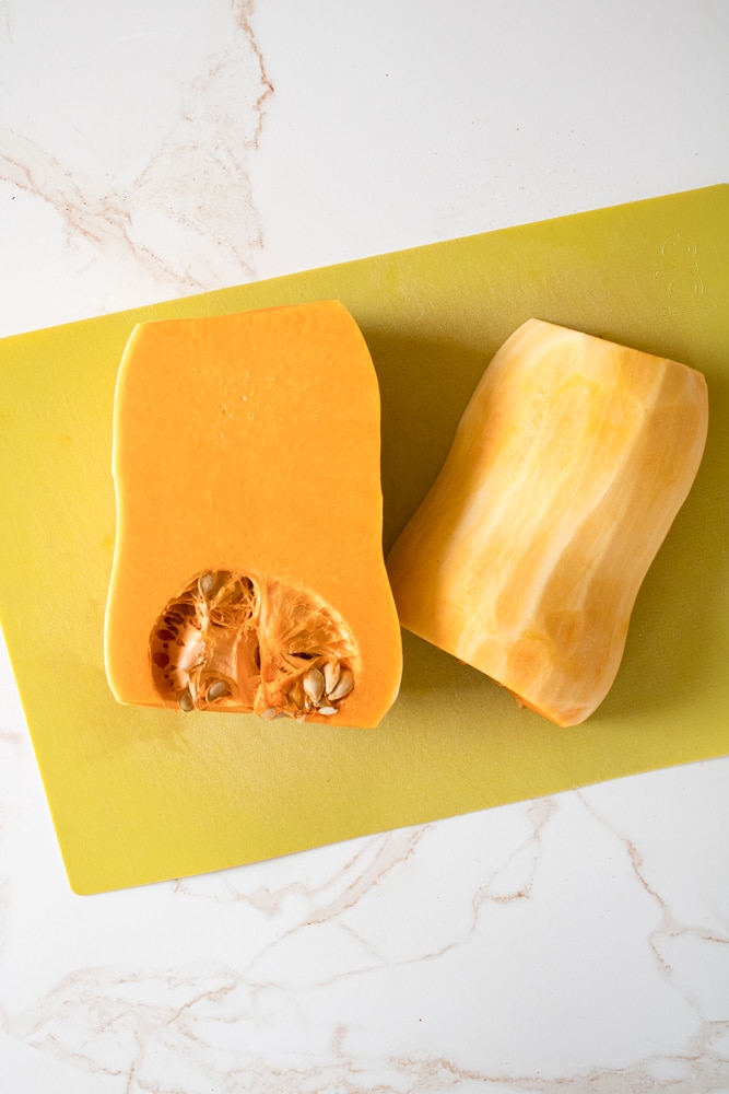 Peel butternut squash cut in half on a cutting mat.