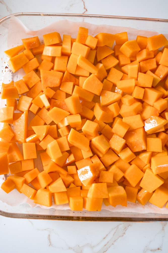 Cut butternut squash cubes in a baking dish.