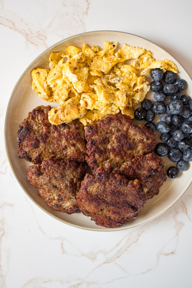 Sausage breakfast platter with patties, scrambled eggs, and blueberries.