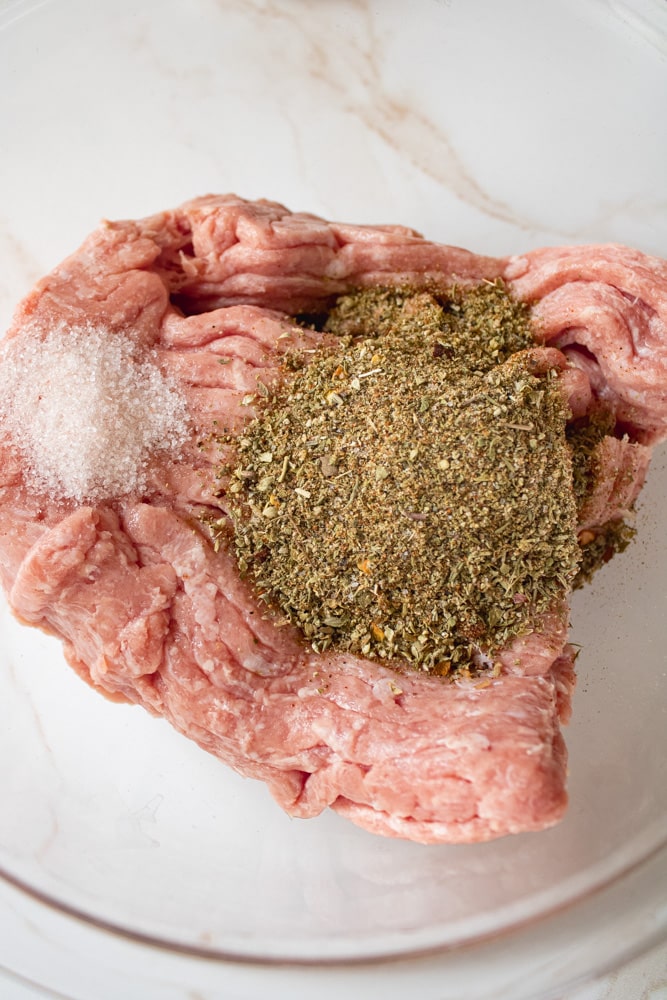 Close up image of ground turkey with sausage seasoning on top in a bowl.