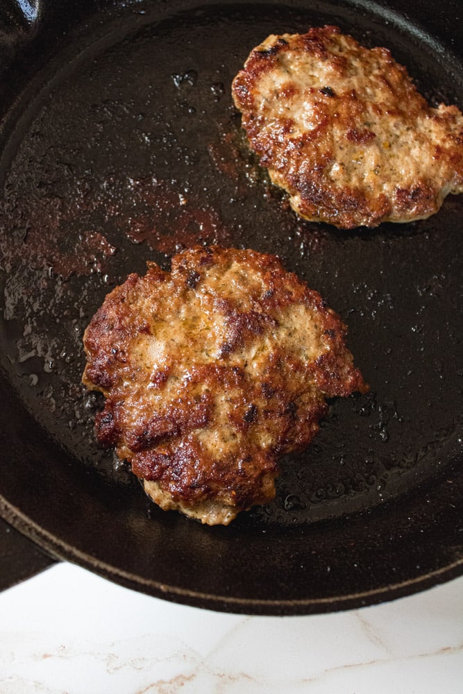 Browned sausage patties in a cast iron skillet.