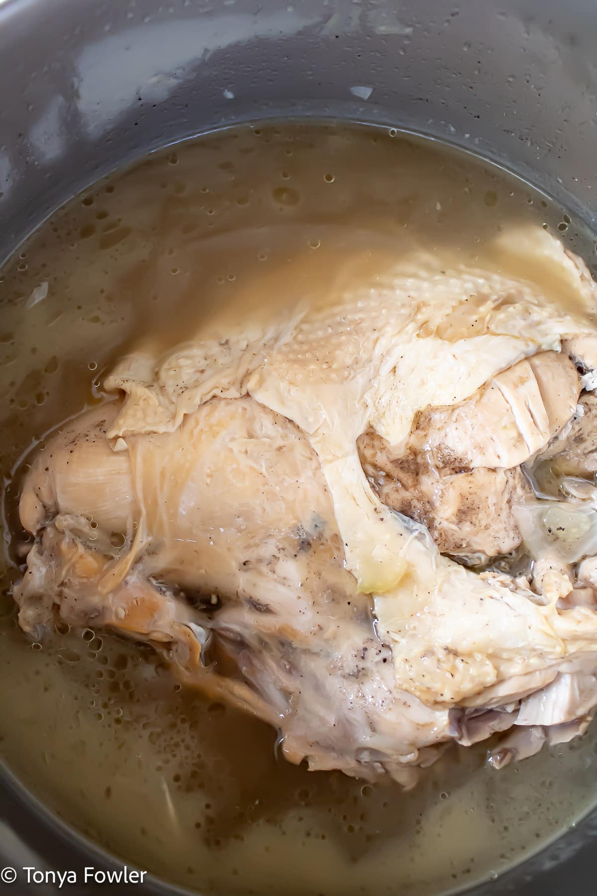 Boiled turkey in a stock pot with broth.