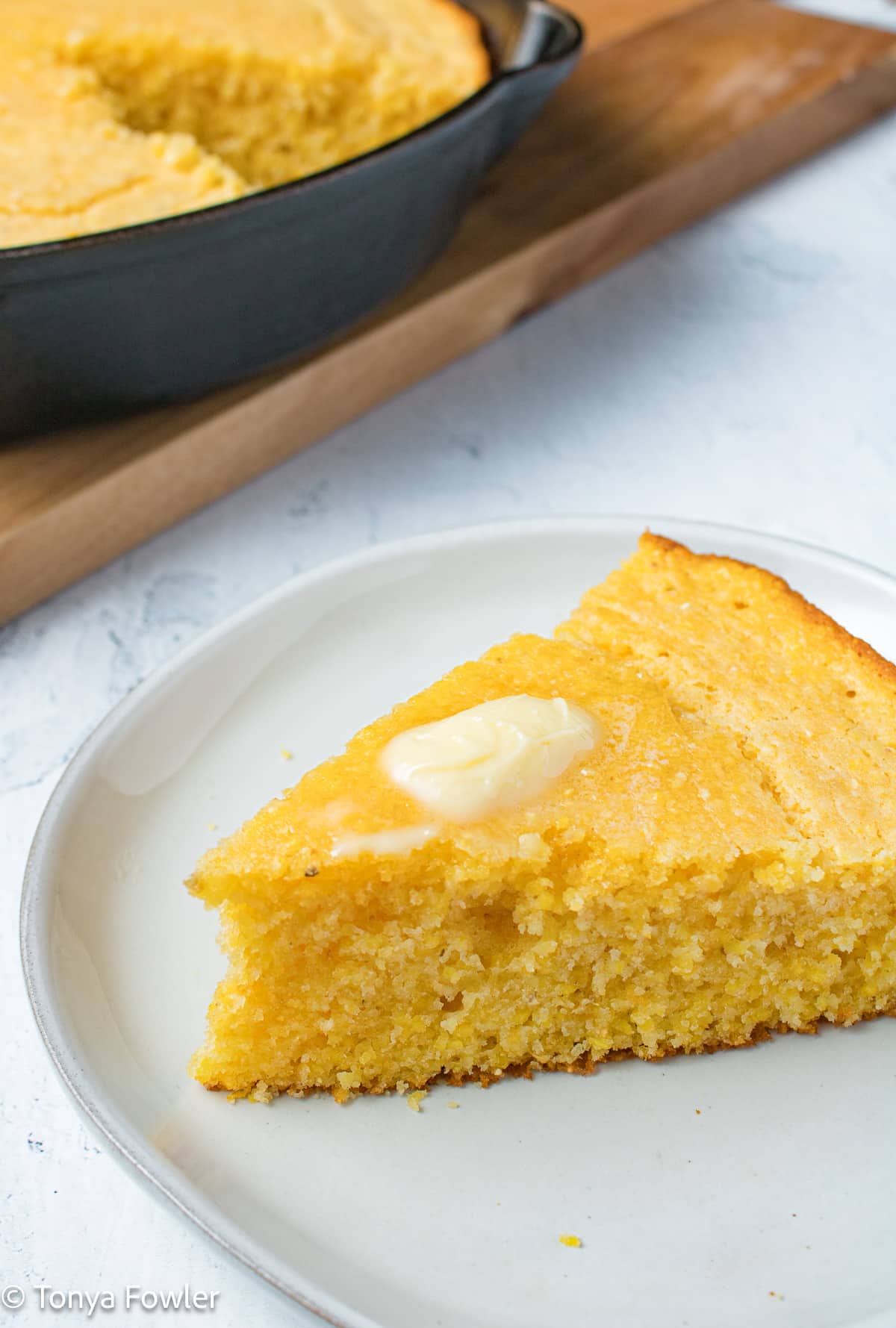 Slice of cornbread on a plate with butter.