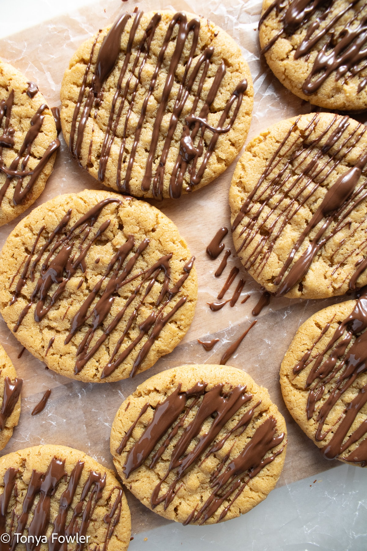 Chocolate drizzled cookies on wax paper. 