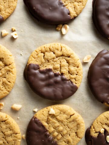 Chocolate dipped cookies on a sheet pan with peanuts.
