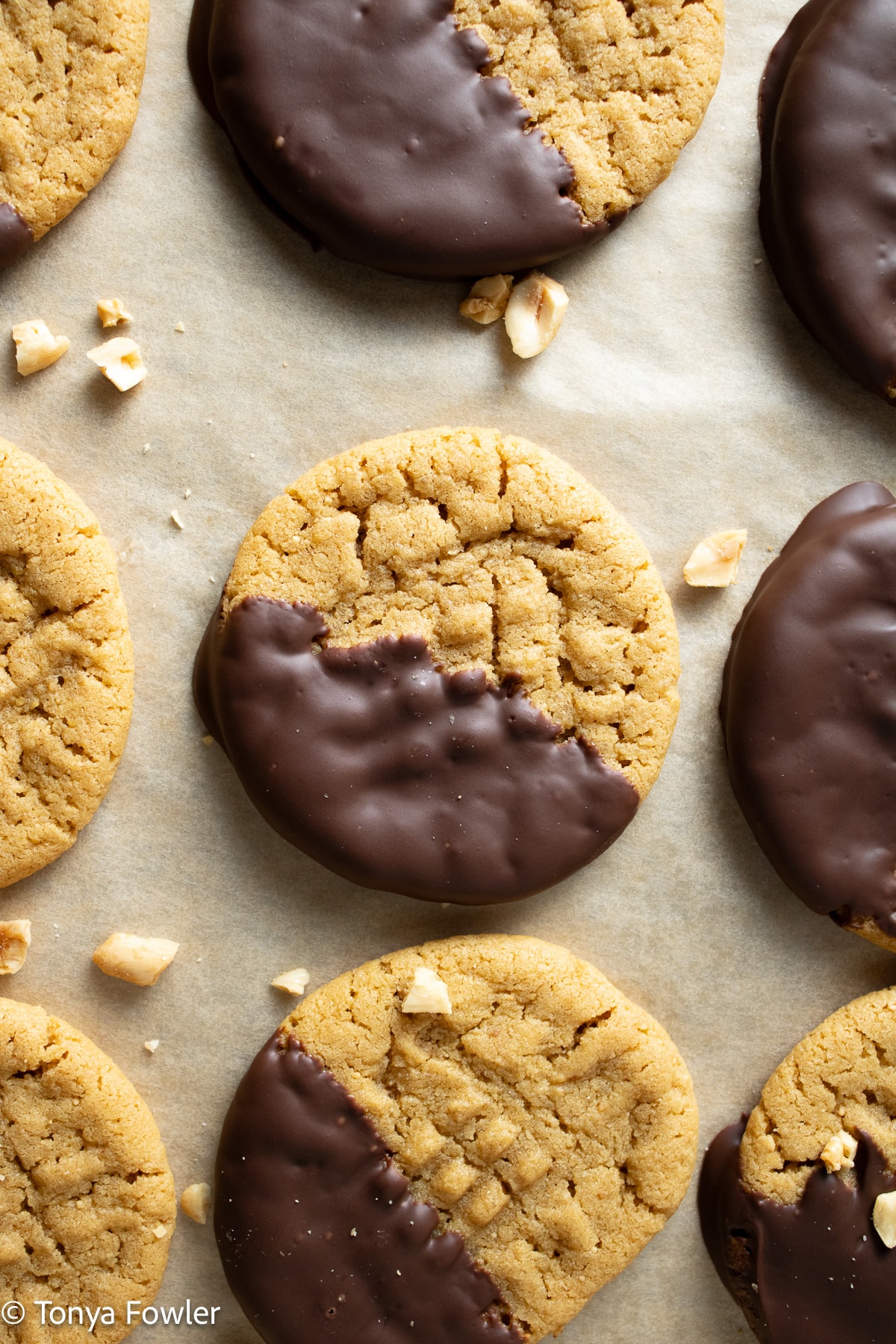 Chocolate dipped cookies on a sheet pan with peanuts.