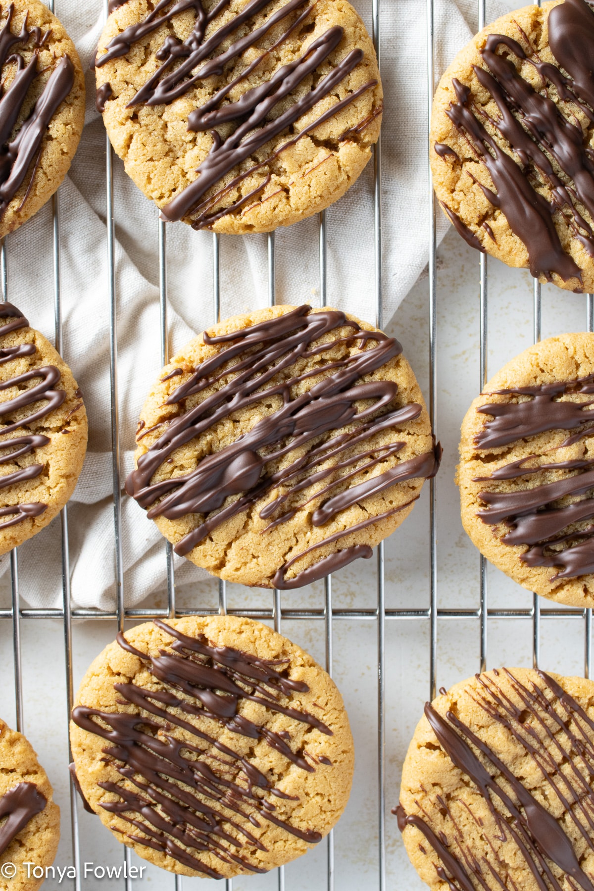 Chocolate drizzled cookies on a wire rack.