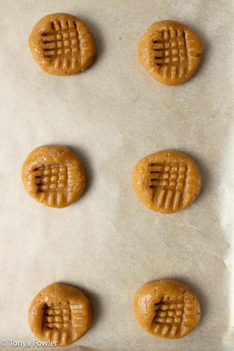 Cookie dough balls on parchment paper lined sheet pan.