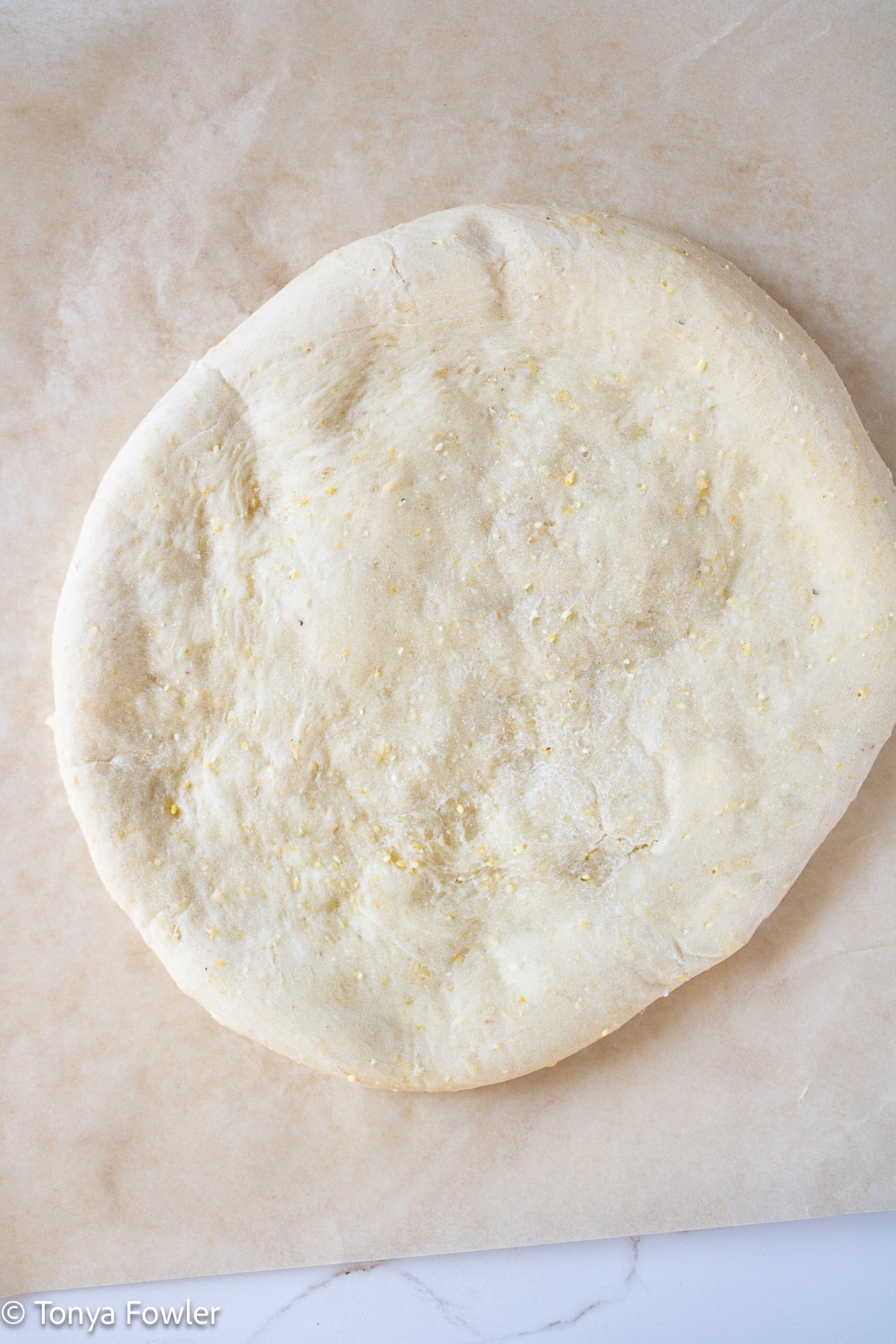 Baked pizza crust on parchment paper.