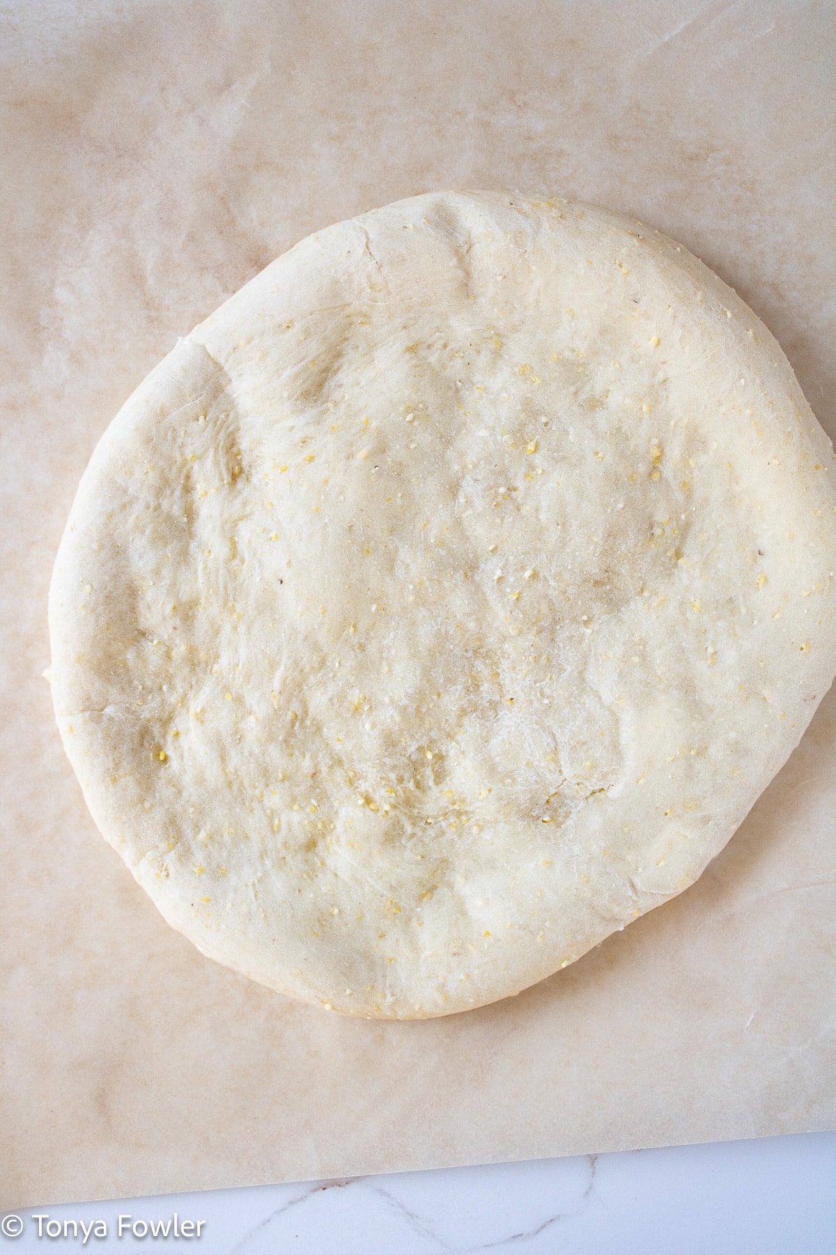 Baked pizza crust on parchment paper.