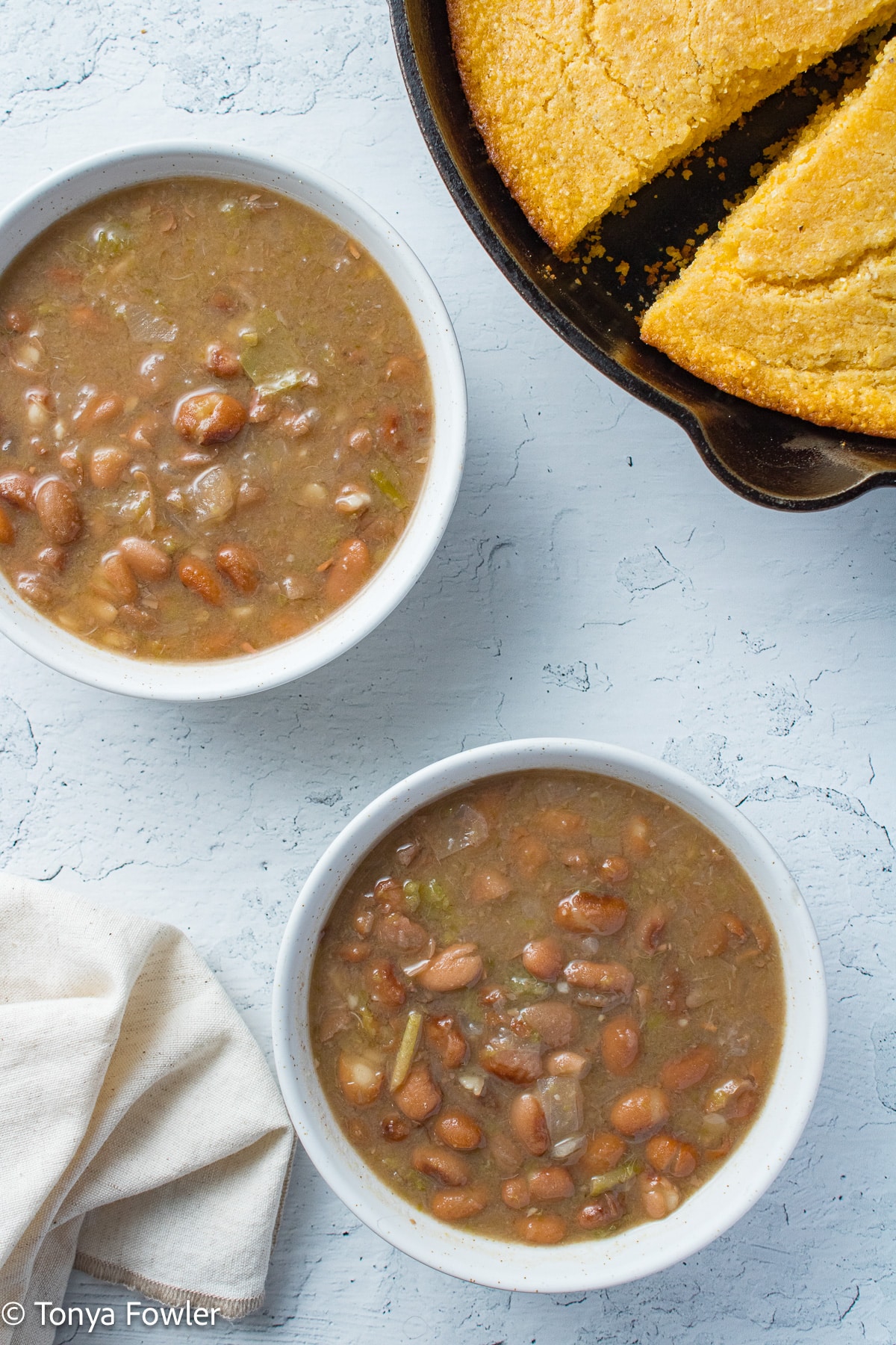 Beans in bowls with cornbread in a skillet near by. 