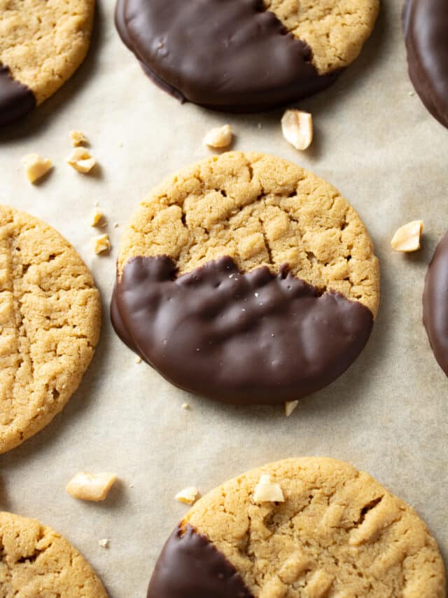 Chocolate dipped peanut butter cookies on a cookie sheet.