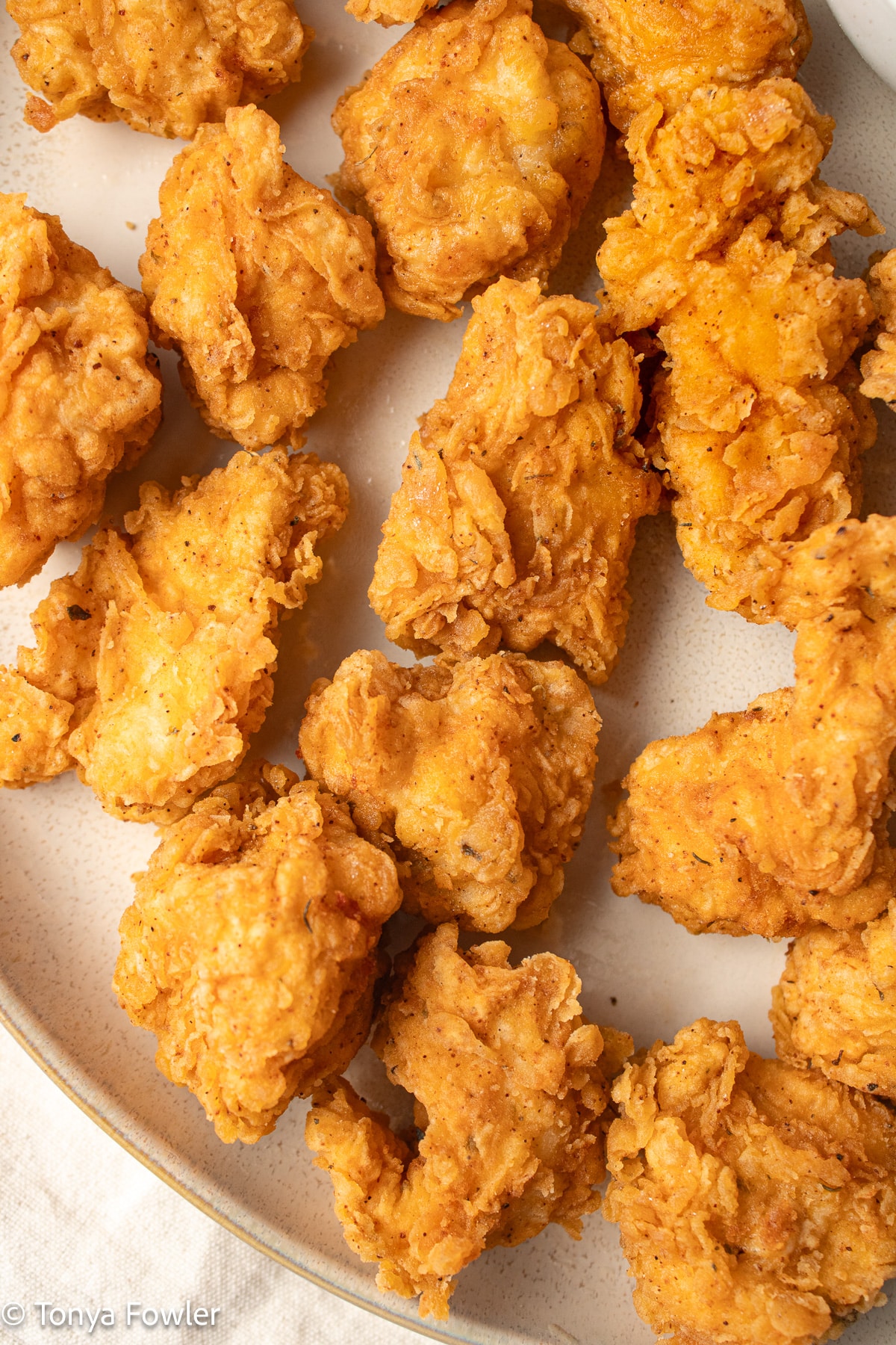 Close up image of fried chicken nuggets on a plate.