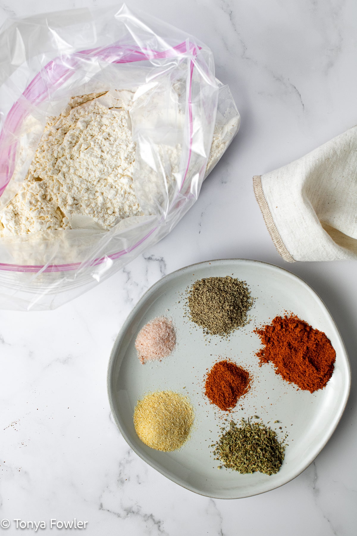 Seasonings on a plage and flour in a gallon bag.