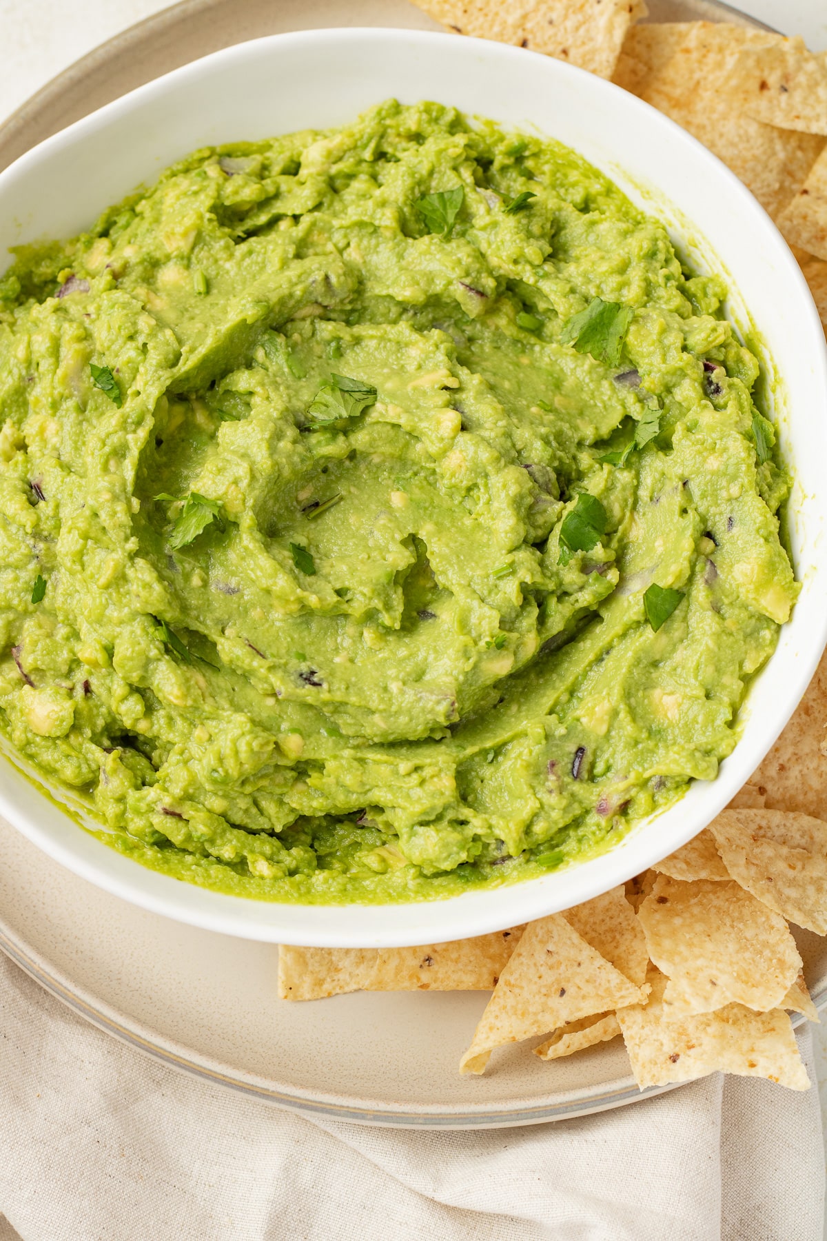 4-ingredient guacamole in a bowl with chips on a plate.