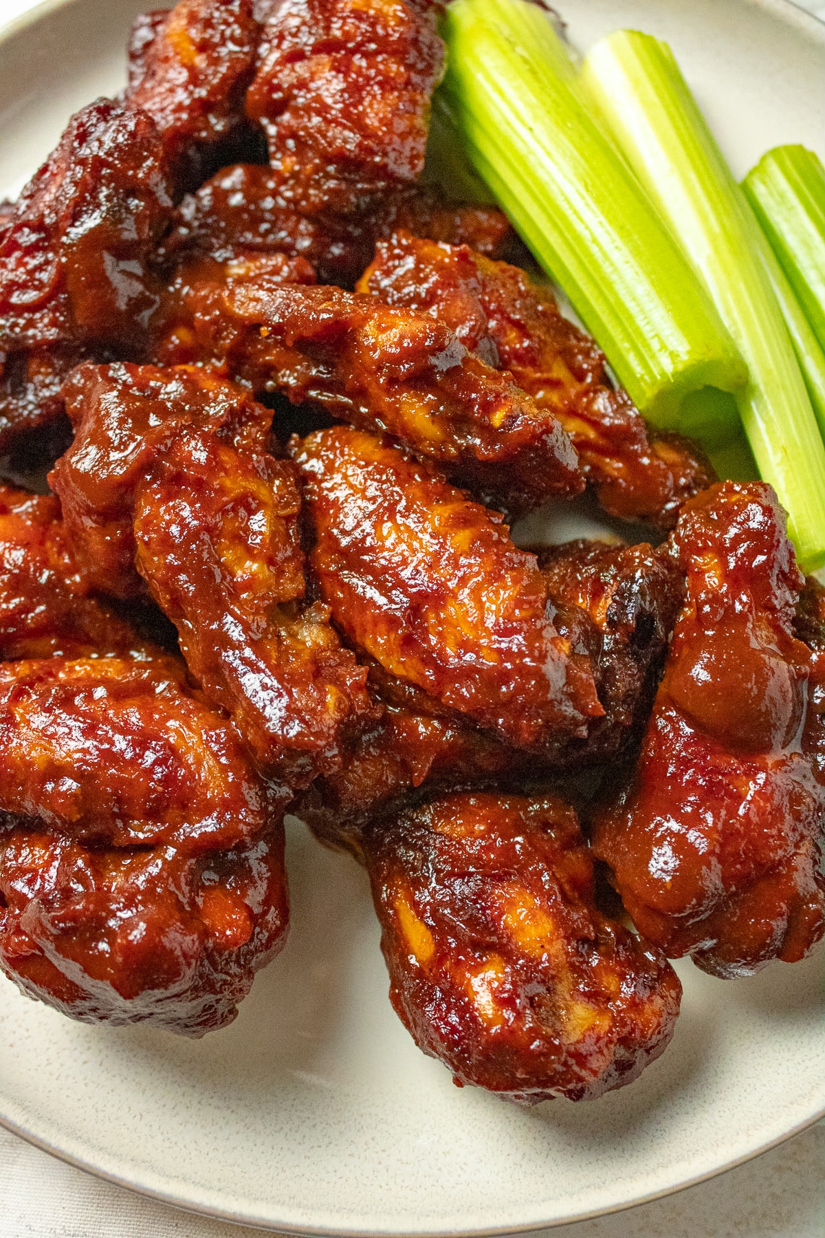 BBQ wings on a plate with celery sticks.