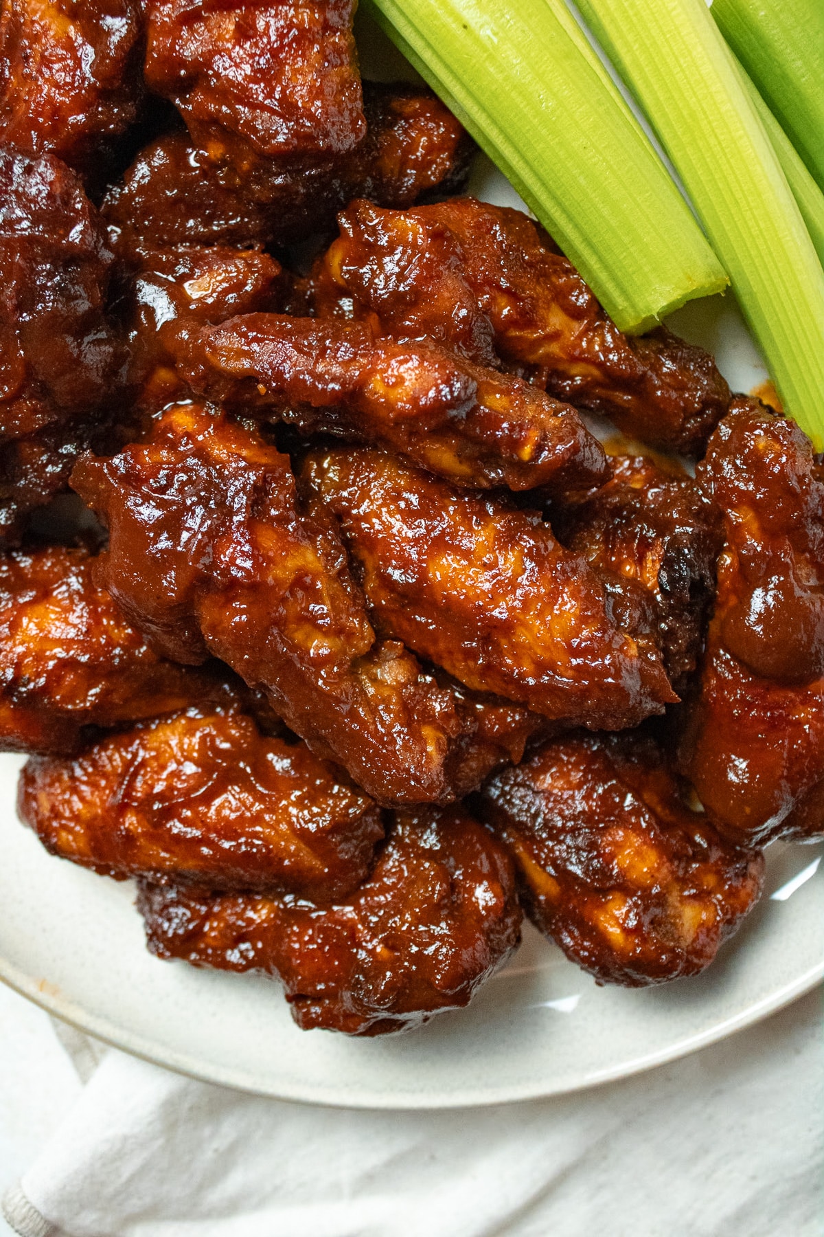 BBQ chicken wings on a plate with celery sticks.