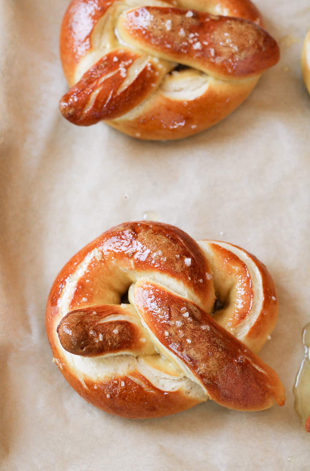 Baked soft pretzel on a sheet pan brushed with garlic butter.