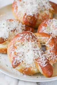 Close up image of a soft pretzel on a plate topped with parmesan cheese.