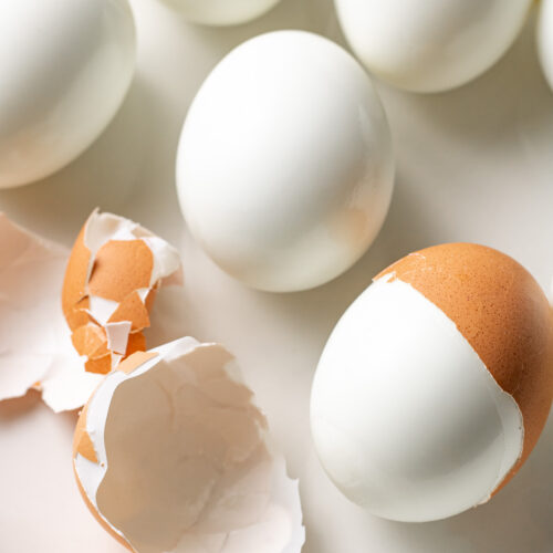 Hard boiled eggs on a plate with half peeled.