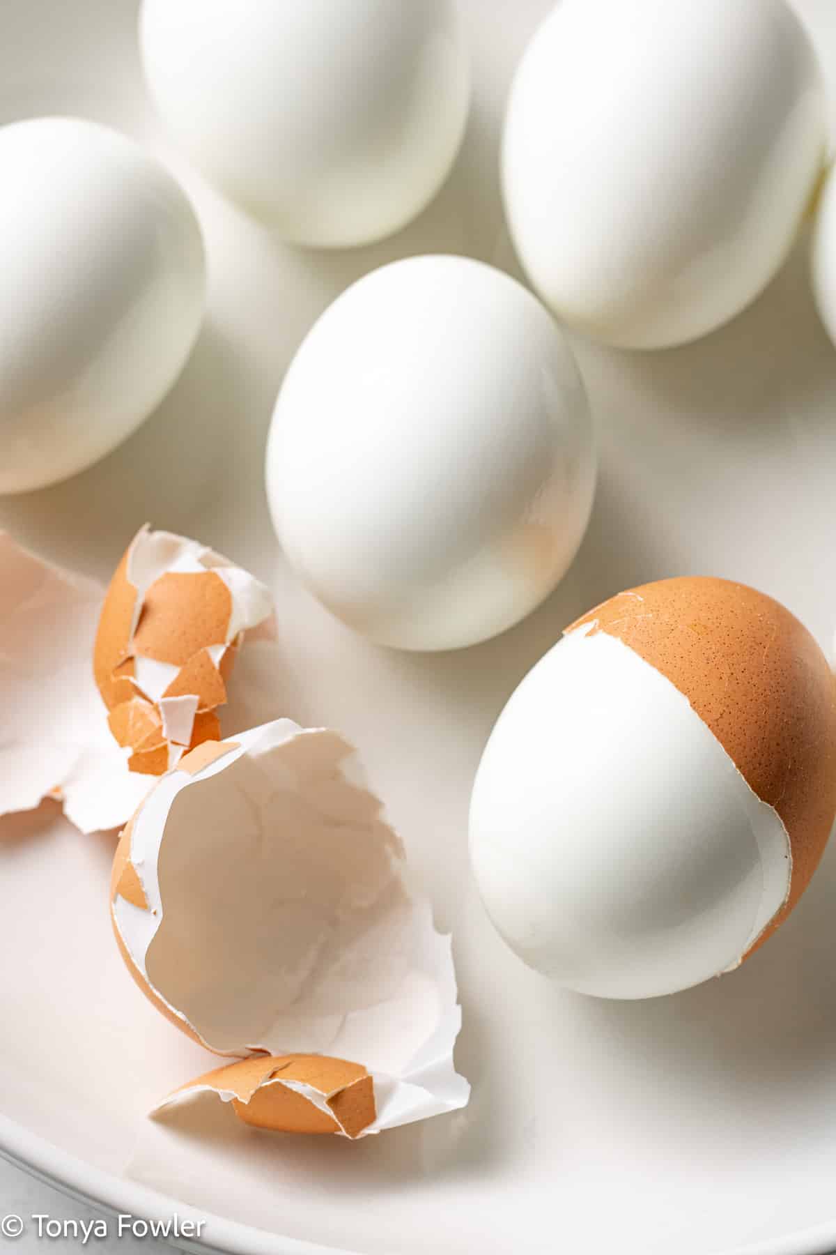 Hard boiled eggs on a plate with half peeled. 