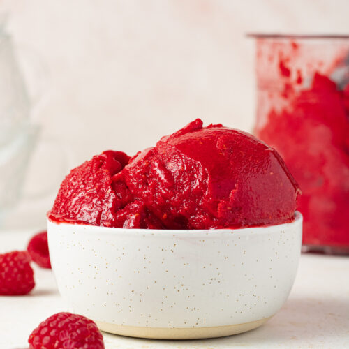 Side view of a bowl of raspberry sorbet in a bowl.