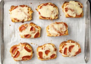 Baked pizza toasts on a sheet pan.