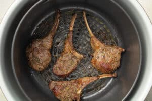 Cooked lamb chops in an air fryer basket.