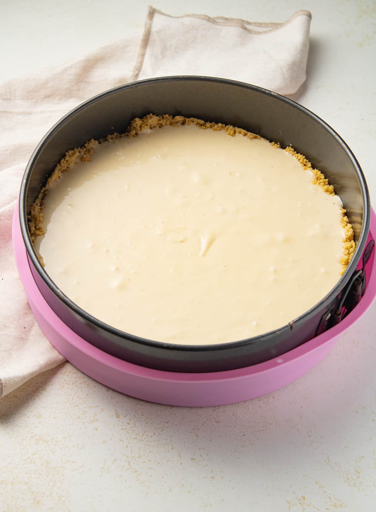 Cheesecake batter in a springform pan in a silicone sleeve on the counter.
