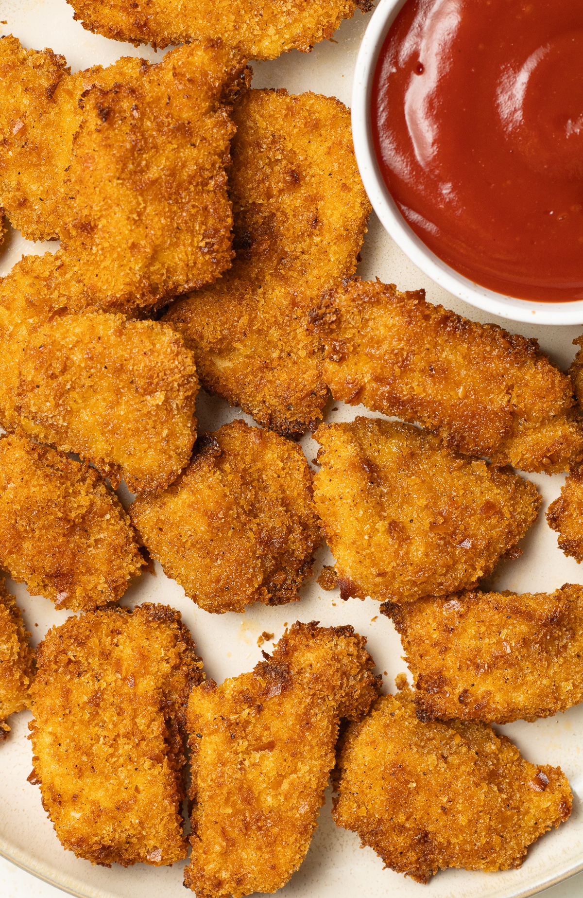 Chicken nuggets on a plate with a bowl of ketchup.