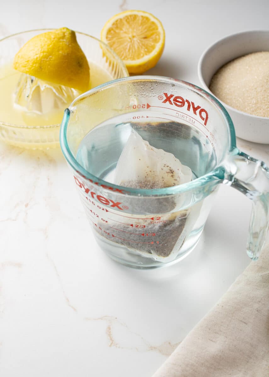 3/4 view of a tea bag steeping in a measuring cup.