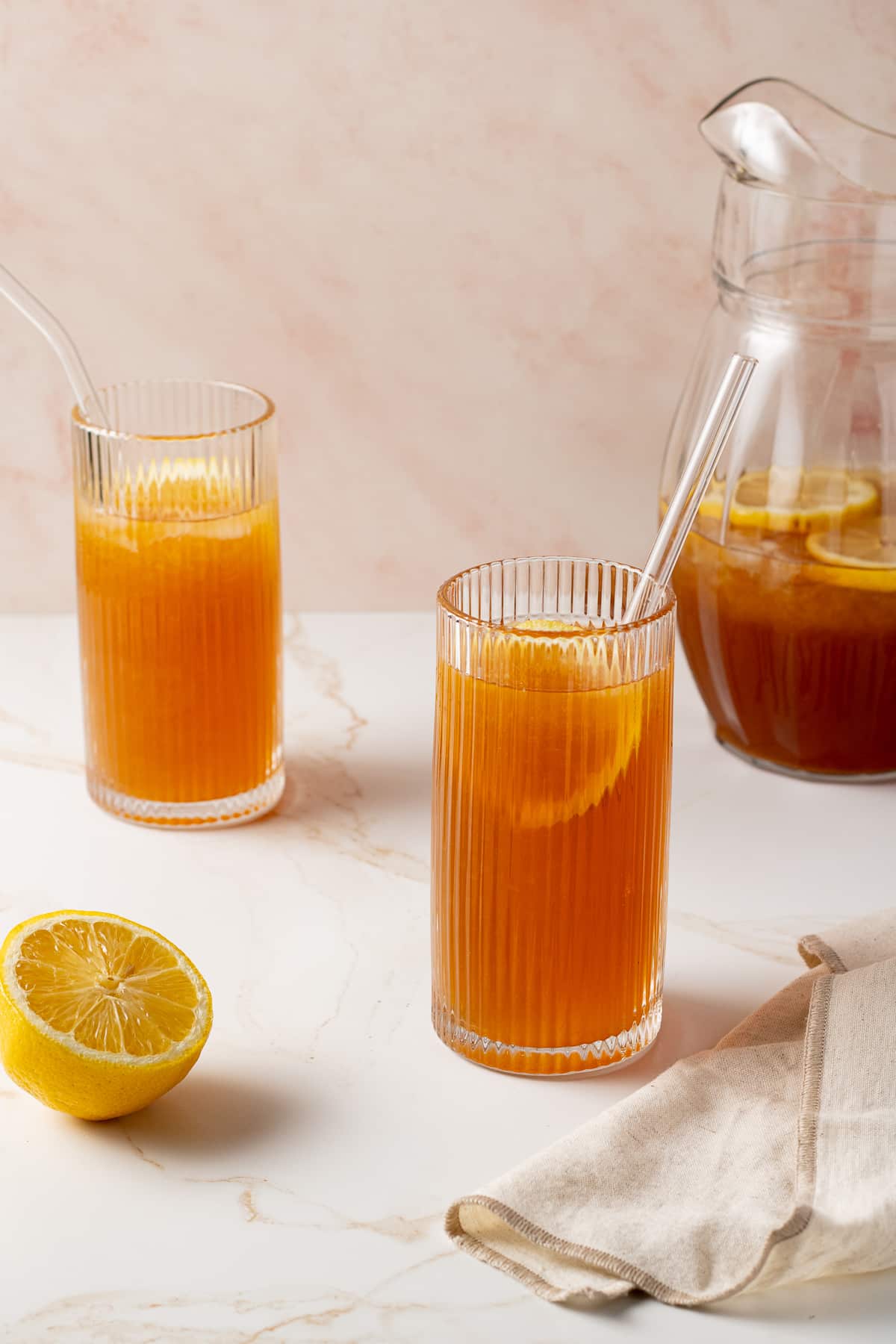 Iced tea in glasses with lemon slices and a lemon half on the counter.