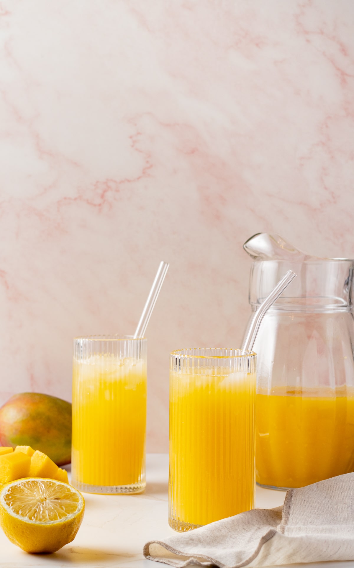 Mango lemonade in glasses with a lemon slice near by.