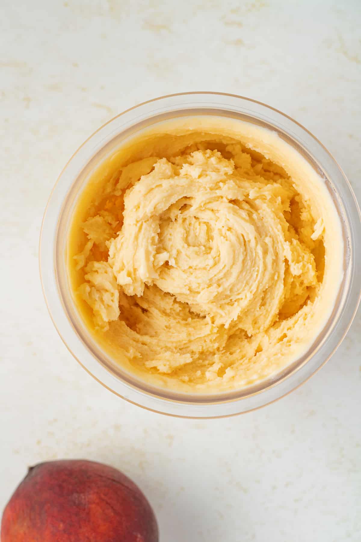 Close up image of frozen peach ice cream in a container.