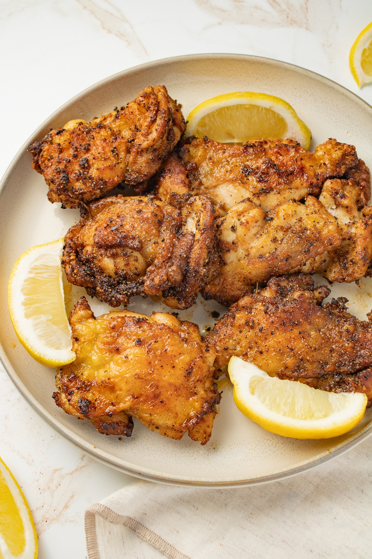 Close up image of chicken thighs on a plate with lemon.