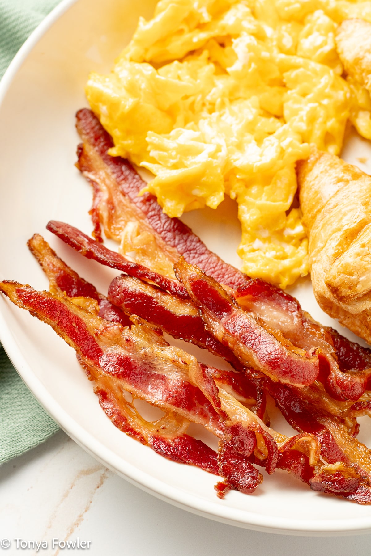Close up image of bacon on a plate with eggs.