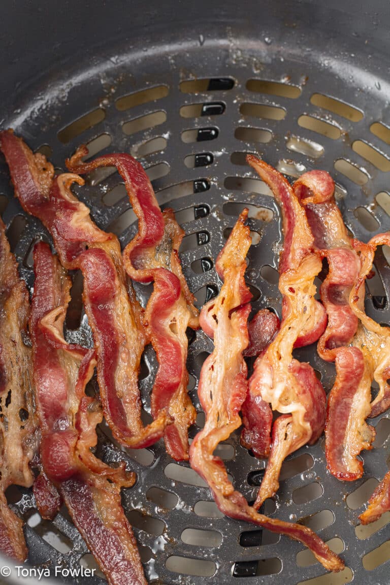 Cooked bacon in an air fryer basket.