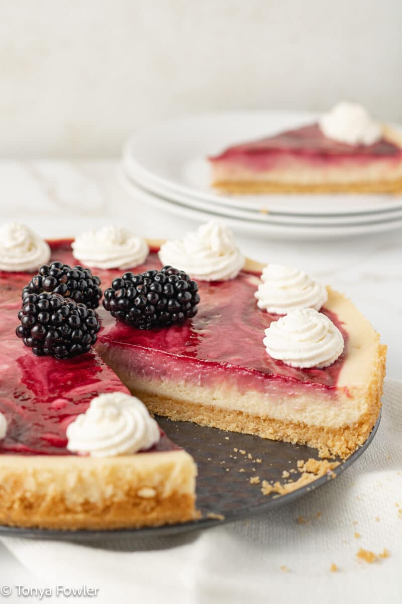 Straight on view of a blackberry cheesecake on a serving tray.