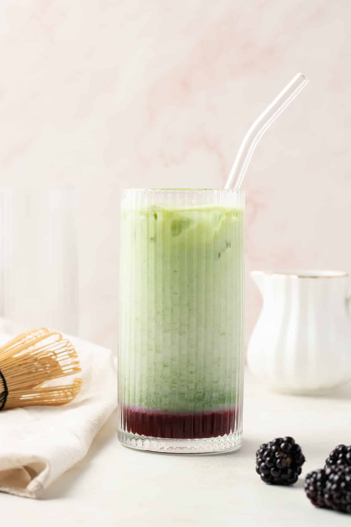 Side view blackberry matcha latte in a cup.