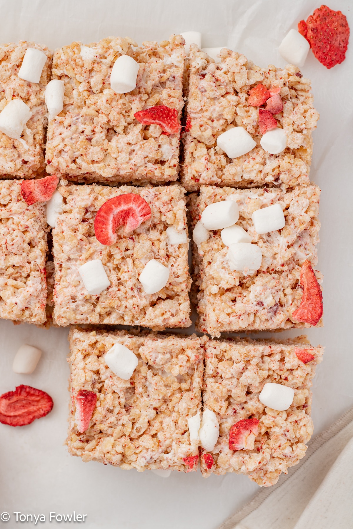 Rice krispie treats with mini marshmallows and strawberries on top.