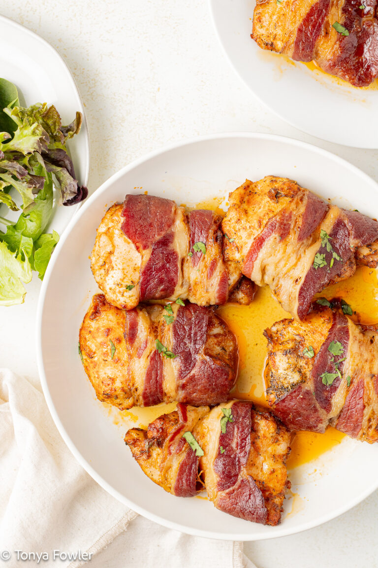 Bacon wrapped chicken thighs on a plate.