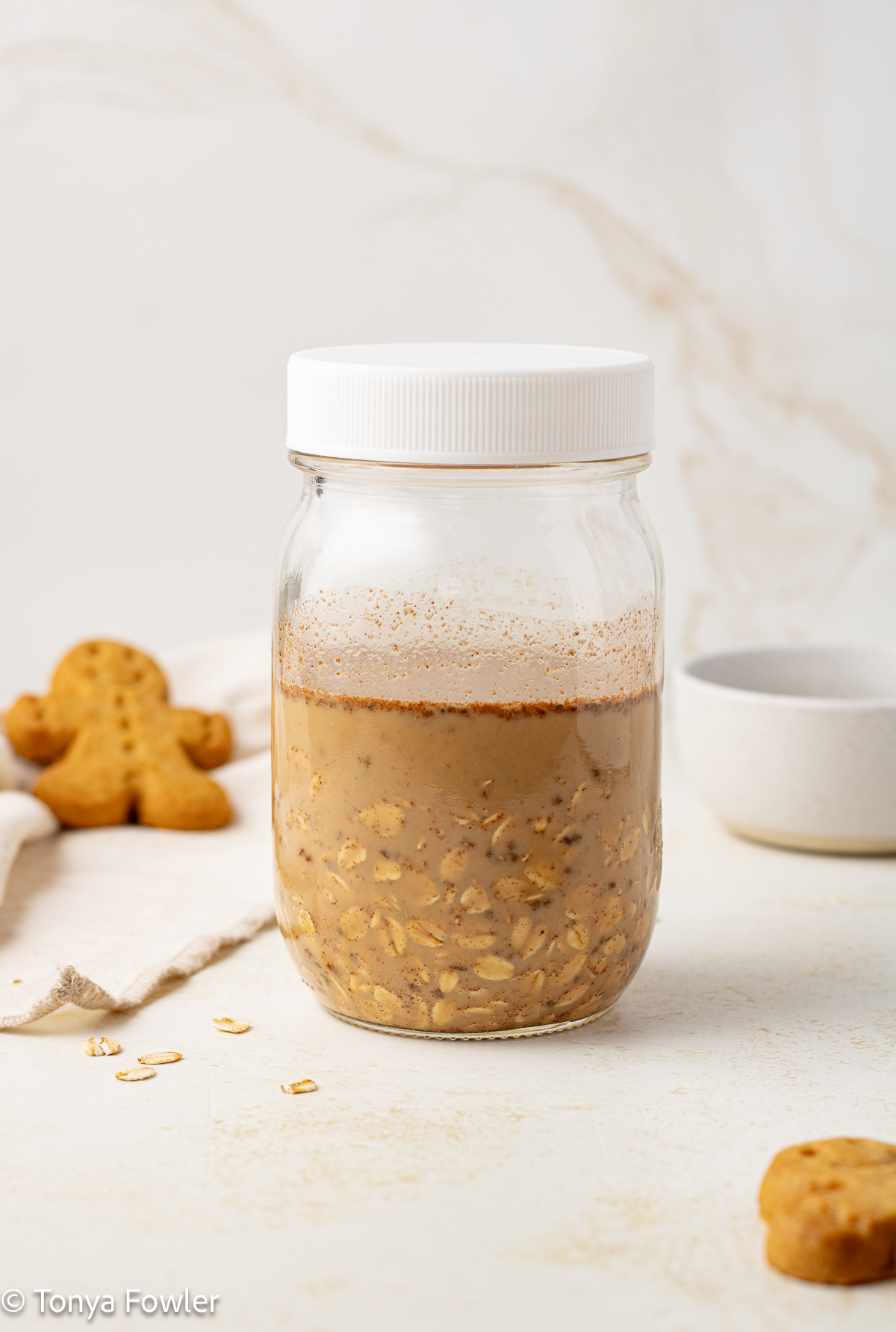 Straight on view of milk, spices and rolled oats in a mason jar. 