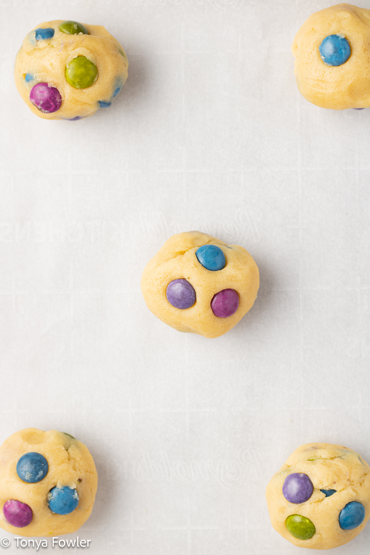 M&M cookie dough balls on a sheet pan.